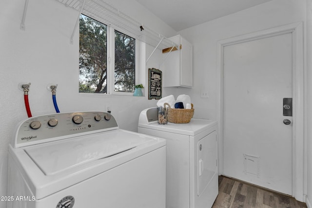 clothes washing area with laundry area, washing machine and dryer, and wood finished floors