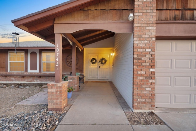 exterior entry at dusk featuring brick siding