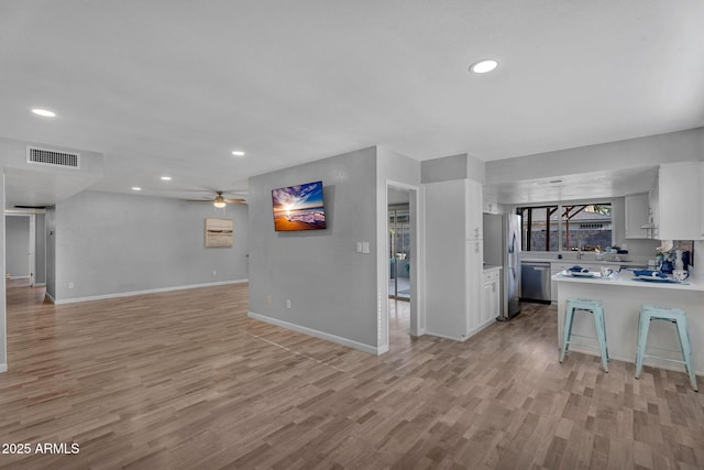 kitchen with light wood-style floors, light countertops, stainless steel appliances, open floor plan, and visible vents