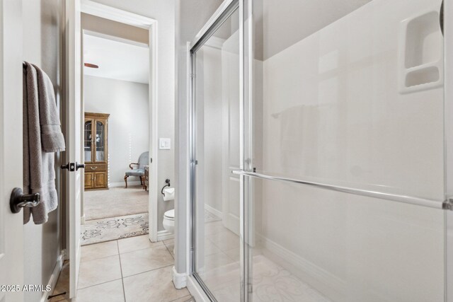 bathroom with toilet, tile patterned floors, and a shower with shower door