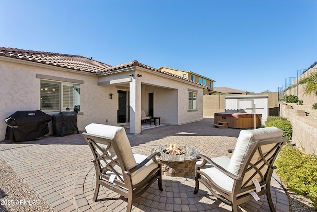 view of patio featuring an outdoor fire pit, a hot tub, and a grill