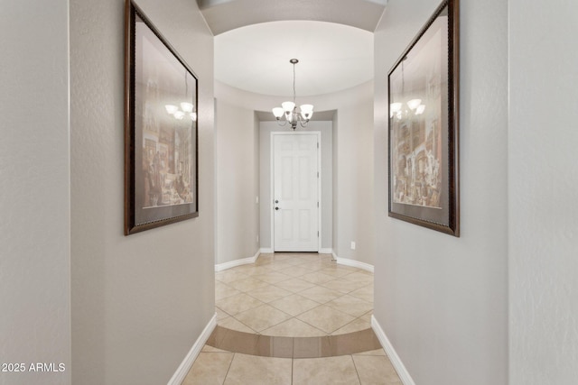 hall with light tile patterned floors and a notable chandelier