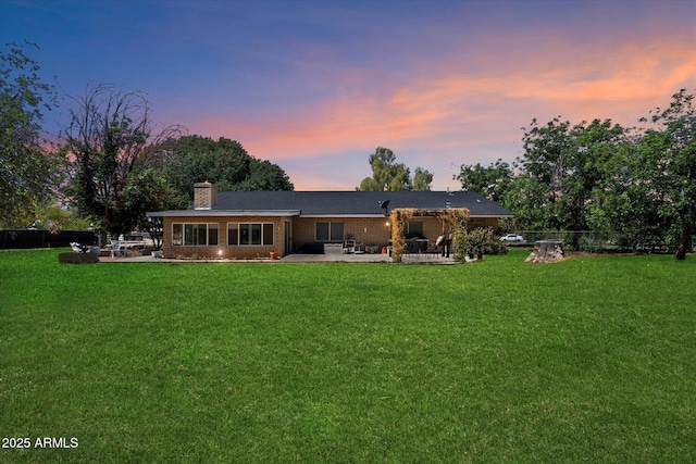 23265 S Via Del Arroyo, Queen Creek, AZ 85142 - back of house at dusk featuring a patio area, a chimney, and brick siding