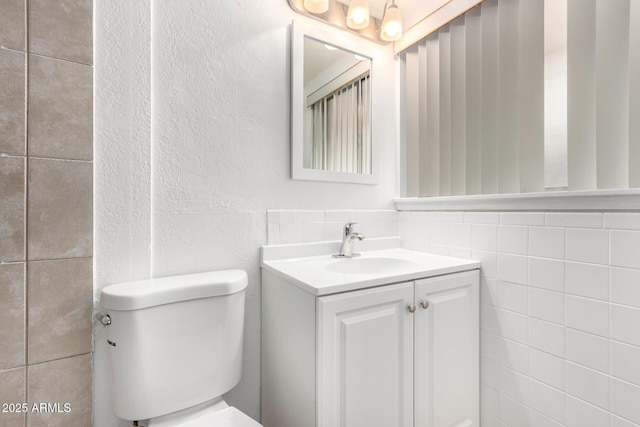 bathroom featuring tile walls, vanity, and toilet