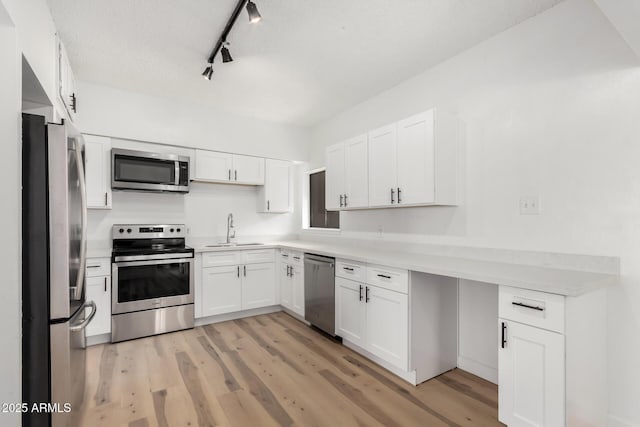 kitchen with sink, a textured ceiling, appliances with stainless steel finishes, light hardwood / wood-style floors, and white cabinets