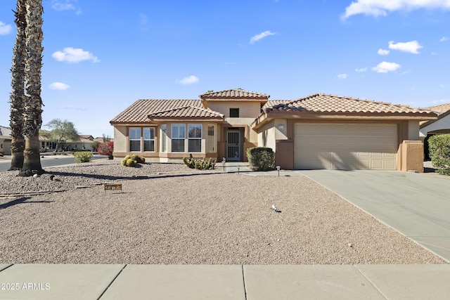 mediterranean / spanish home featuring driveway, a tiled roof, a garage, and stucco siding