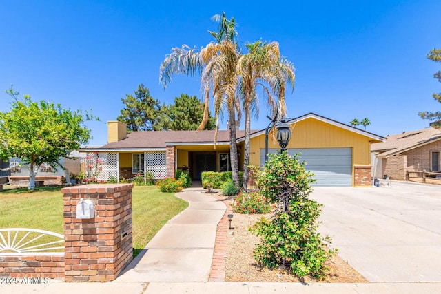 ranch-style home featuring a chimney, driveway, brick siding, a garage, and a front lawn