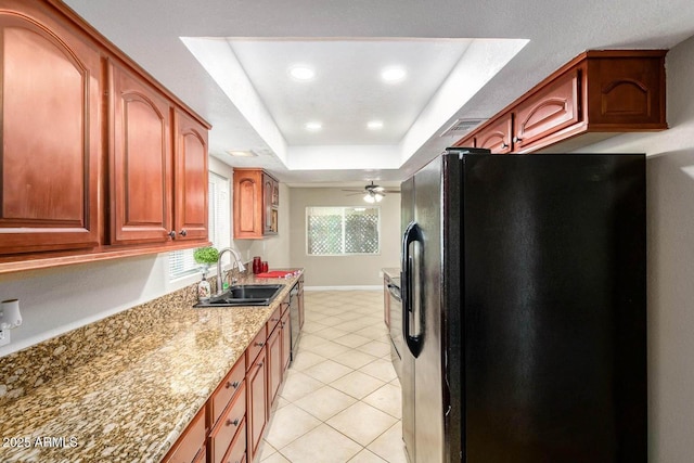 kitchen with a sink, visible vents, black fridge, light tile patterned floors, and a tray ceiling