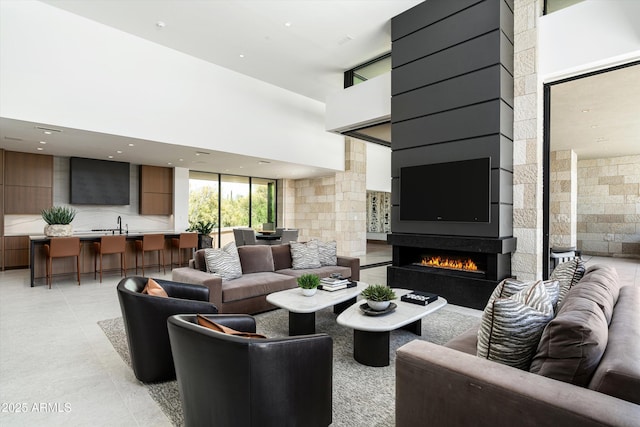 tiled living room with a towering ceiling and a wall of windows