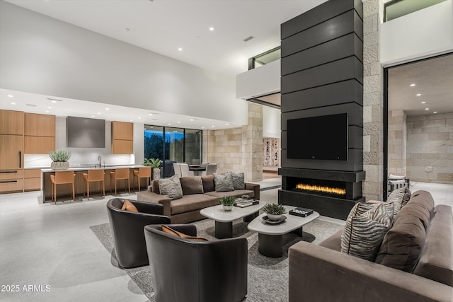 living room featuring sink, a towering ceiling, and a fireplace