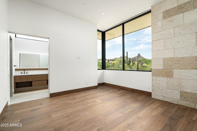 unfurnished bedroom featuring wood-type flooring, connected bathroom, and sink