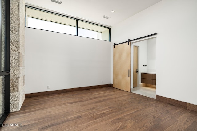 unfurnished room featuring hardwood / wood-style floors and a barn door