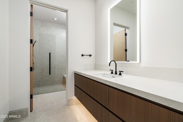 bathroom with tile patterned flooring, vanity, and a tile shower