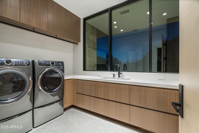 clothes washing area featuring washer and dryer, sink, and cabinets