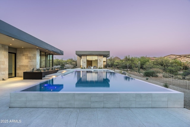 pool at dusk with a patio area