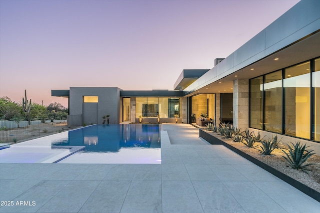 pool at dusk featuring a patio area