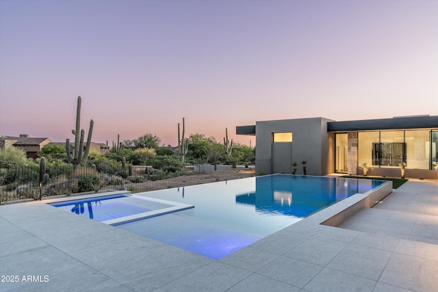 pool at dusk featuring a patio