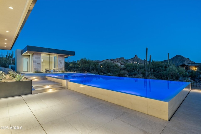 view of swimming pool featuring a mountain view, an outbuilding, and a patio