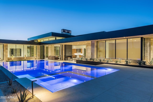 pool at dusk featuring an in ground hot tub and a patio area