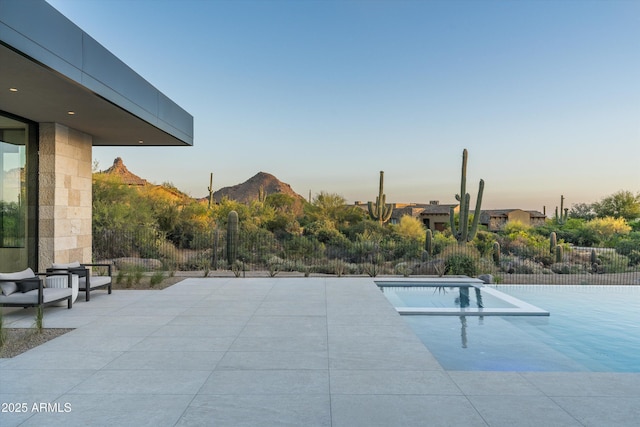 pool at dusk with a mountain view and a patio