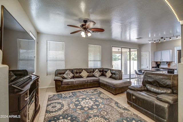 tiled living room with rail lighting and ceiling fan