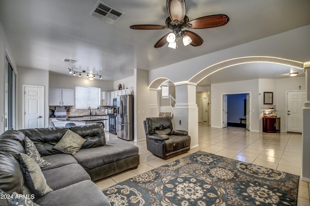 living room with decorative columns, light tile patterned floors, ceiling fan, track lighting, and sink