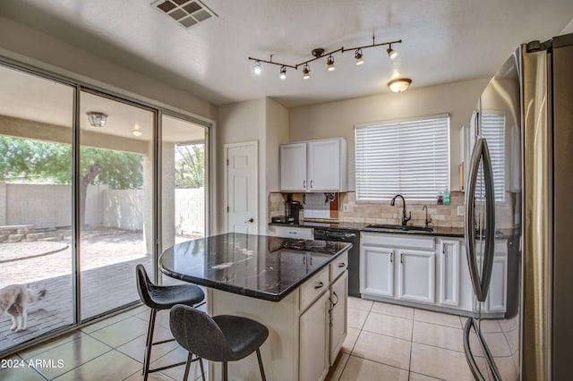 kitchen with light tile patterned flooring, tasteful backsplash, sink, a center island, and stainless steel fridge