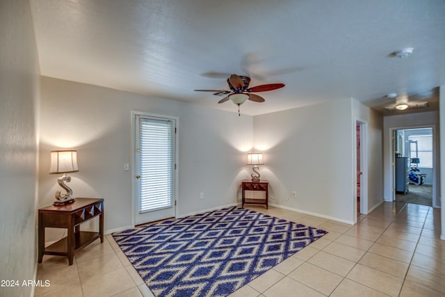 living area with light tile patterned floors and ceiling fan