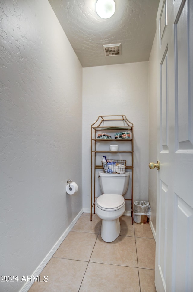 bathroom with toilet, tile patterned floors, and a textured ceiling