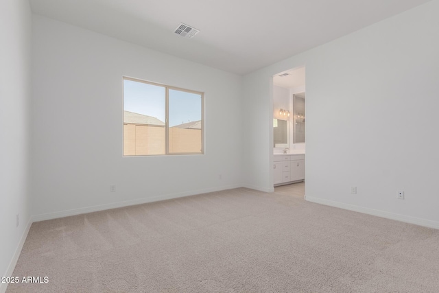 unfurnished bedroom featuring light carpet, connected bathroom, visible vents, and baseboards