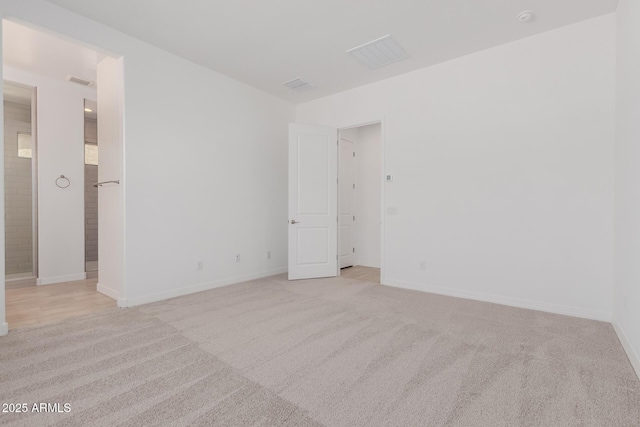 unfurnished room featuring light colored carpet, visible vents, and baseboards