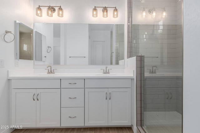 full bathroom with double vanity, a stall shower, and a sink