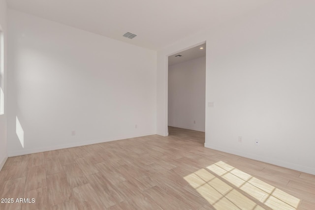 empty room featuring baseboards, visible vents, and light wood finished floors