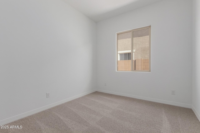 empty room featuring baseboards and light colored carpet