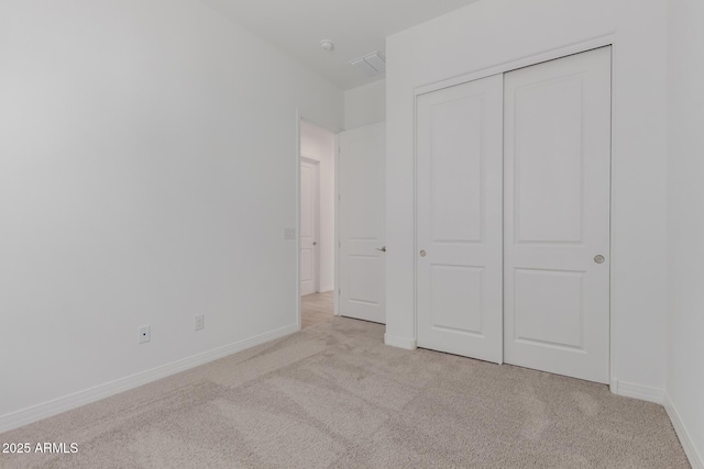 unfurnished bedroom featuring a closet, carpet flooring, visible vents, and baseboards