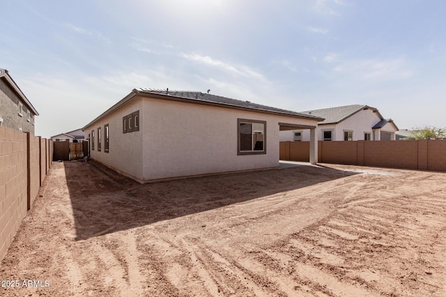 rear view of property featuring a fenced backyard and stucco siding