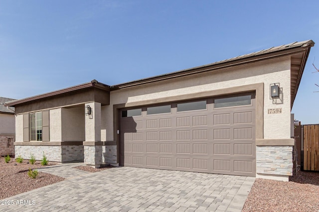 view of front of property with decorative driveway, stone siding, a garage, and stucco siding