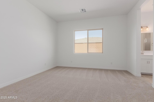 unfurnished room with light carpet, visible vents, and baseboards