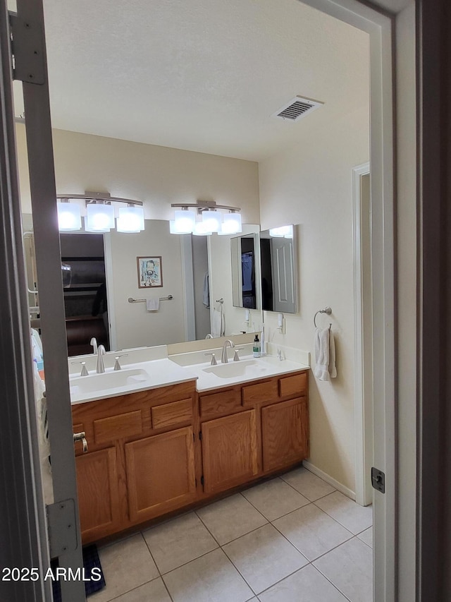 bathroom featuring double vanity, tile patterned flooring, visible vents, and a sink