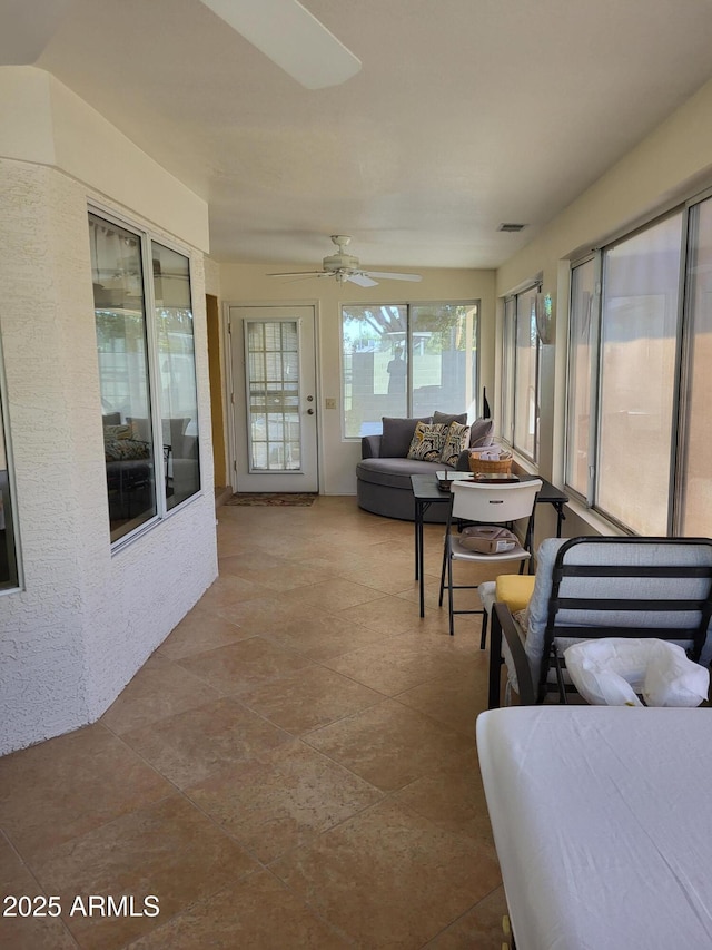 sunroom with a ceiling fan and visible vents