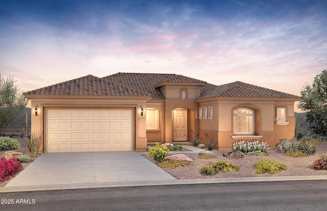 mediterranean / spanish-style house with driveway, a tiled roof, an attached garage, and stucco siding