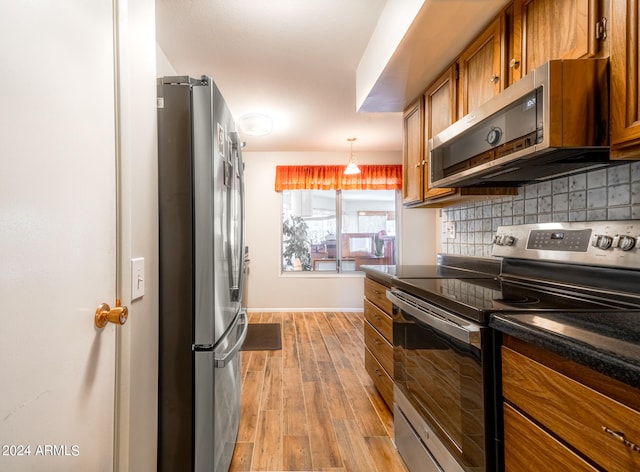 kitchen featuring light wood-type flooring, pendant lighting, stainless steel appliances, and tasteful backsplash