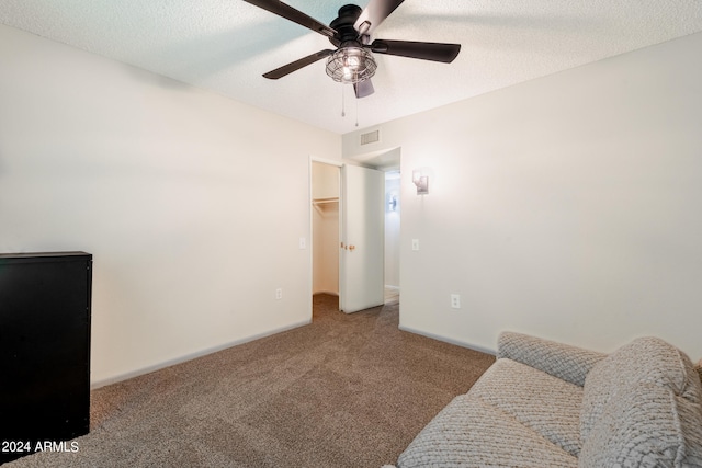 living area with ceiling fan, carpet floors, and a textured ceiling