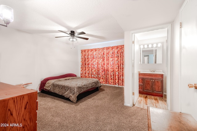 bedroom with ceiling fan, sink, a textured ceiling, carpet floors, and ensuite bath