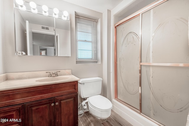 bathroom featuring walk in shower, hardwood / wood-style floors, vanity, and toilet