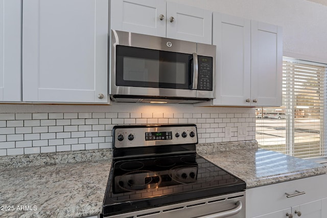 kitchen featuring white cabinetry, backsplash, light stone counters, and appliances with stainless steel finishes