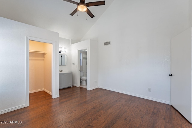 unfurnished bedroom featuring high vaulted ceiling, dark hardwood / wood-style floors, connected bathroom, a spacious closet, and a closet