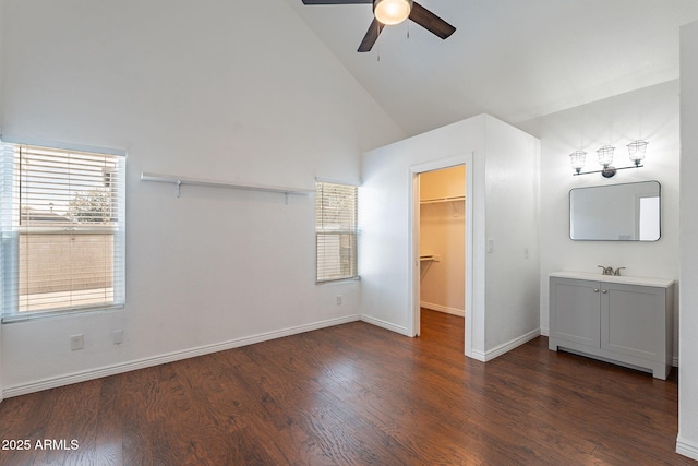 unfurnished bedroom featuring a spacious closet, high vaulted ceiling, dark hardwood / wood-style floors, a closet, and ceiling fan