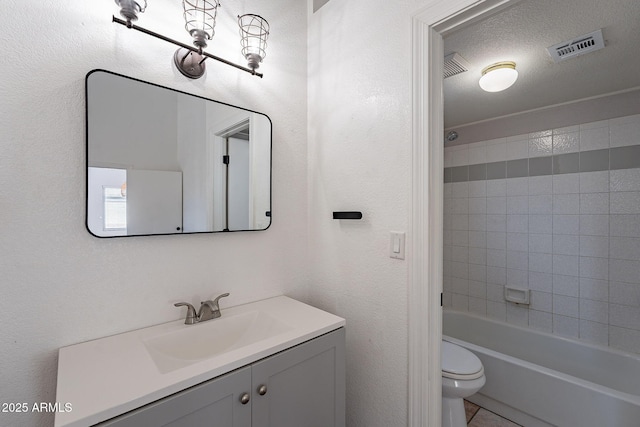 full bathroom with tile patterned flooring, tiled shower / bath combo, vanity, a textured ceiling, and toilet