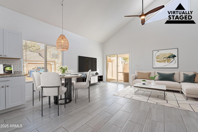 dining room with ceiling fan and high vaulted ceiling